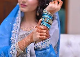 A bride showcases intricate henna designs and vibrant jewelry in traditional attire.